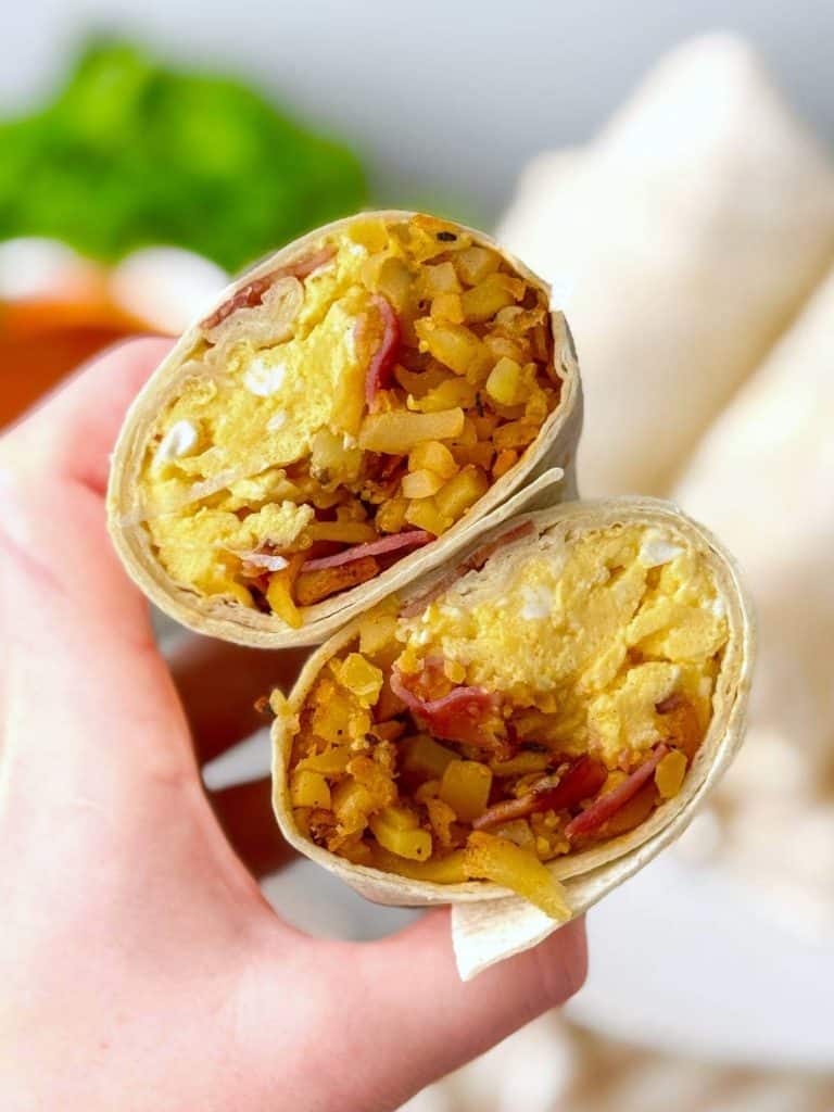 Breakfast burrito cut in half showing scrambled eggs and hash browns