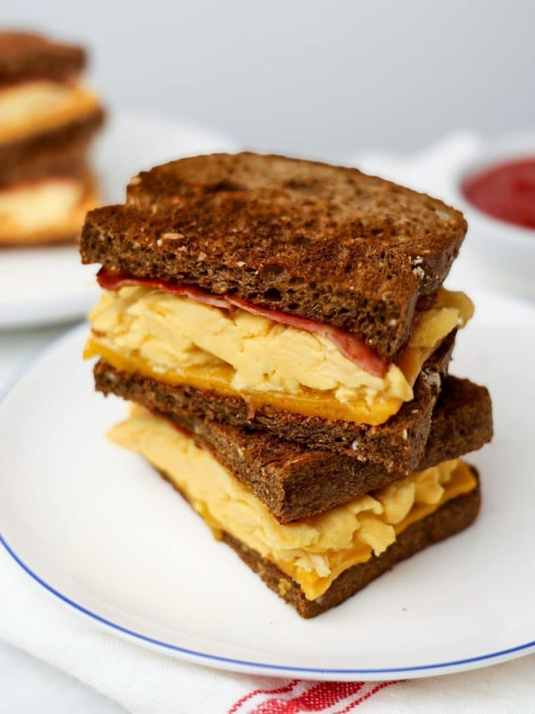 Stacked breakfast sandwiches with scrambled eggs, turkey bacon, and cheese on high-fiber bread