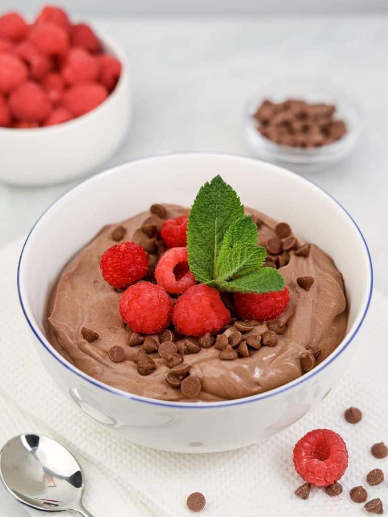 High-protein chocolate yogurt bowl topped with fresh raspberries, mini chocolate chips and mint