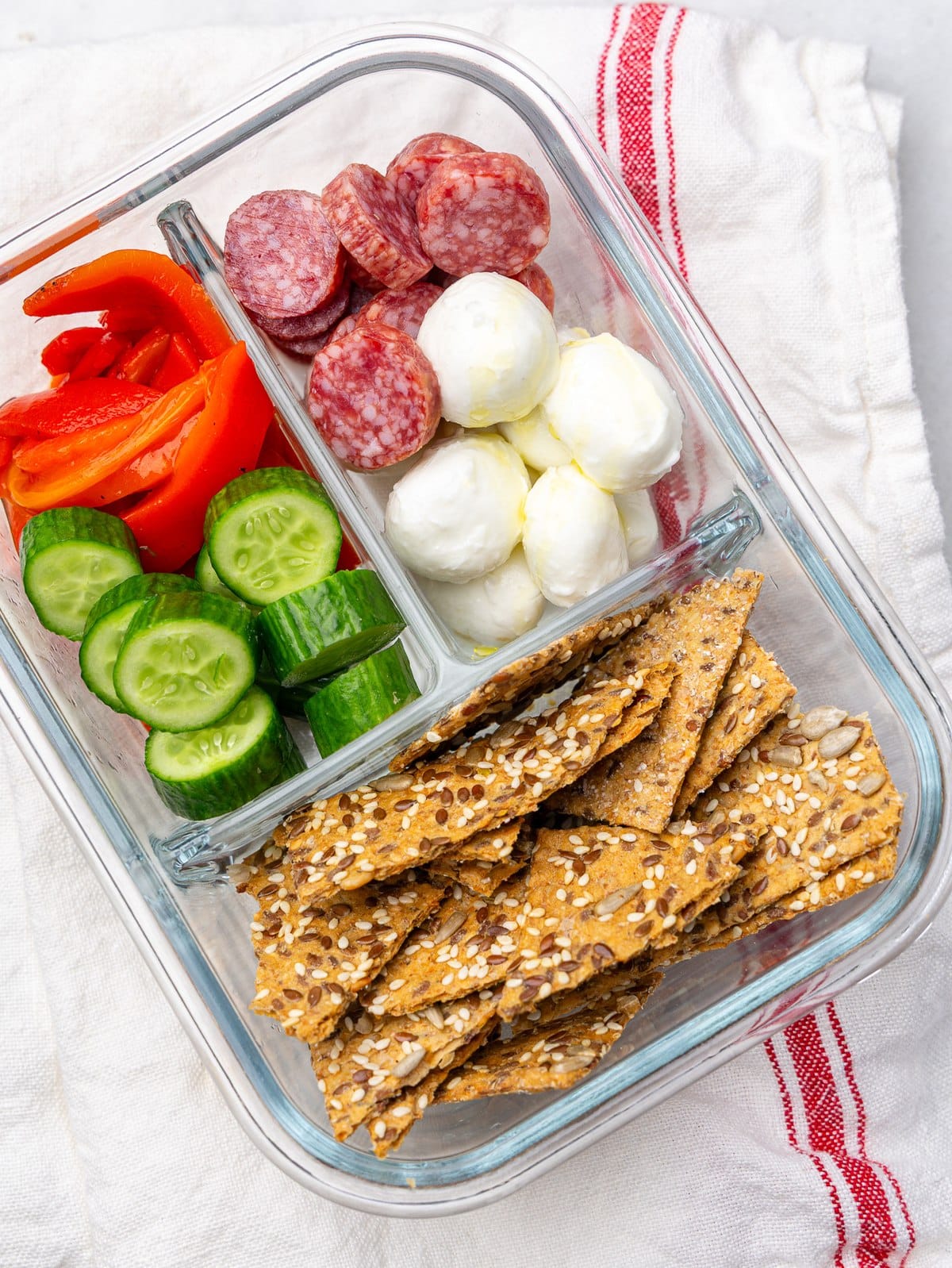 Antipasto snack box with salami, mozzarella pearls, veggies and seeded crackers