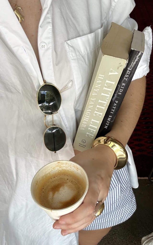 a person holding books and a cup of coffee, showing lifelong learning and personal growth habits