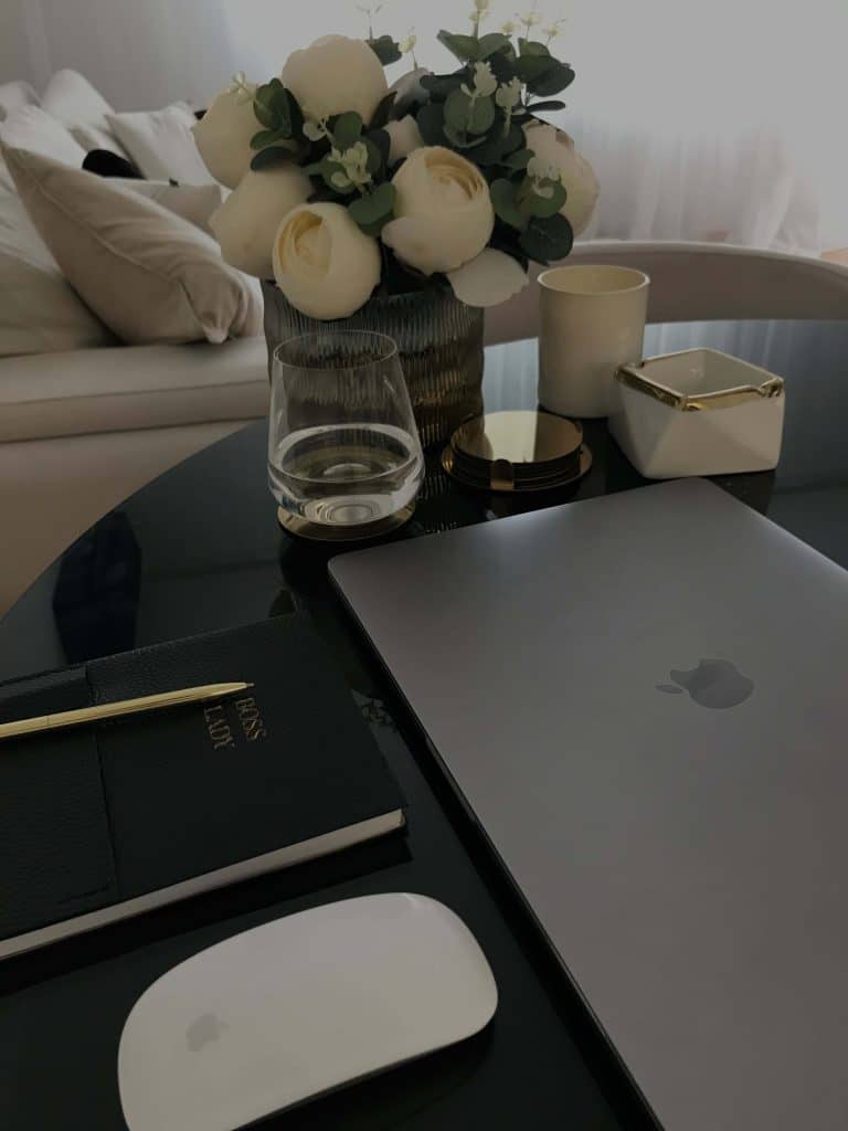a clean workspace with a laptop, notebook, and glass of water, showing productive morning habits for success