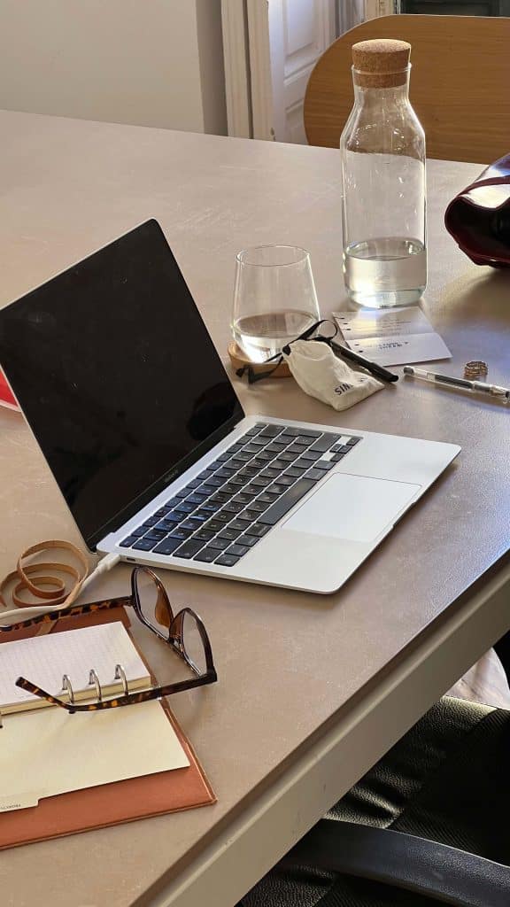 a minimal home office desk with laptop, flowers, and planner, representing organized work and focus habits