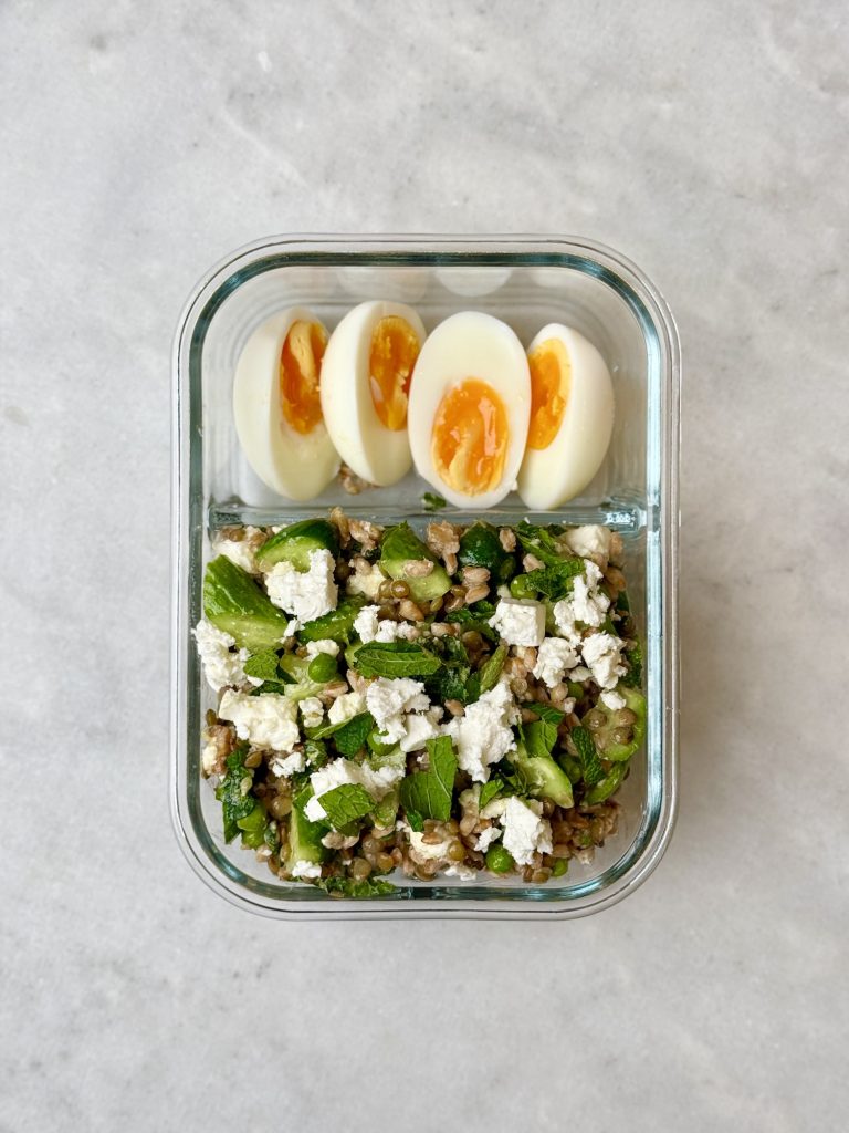 Mediterranean farro salad meal prep with soft-boiled eggs in a glass container