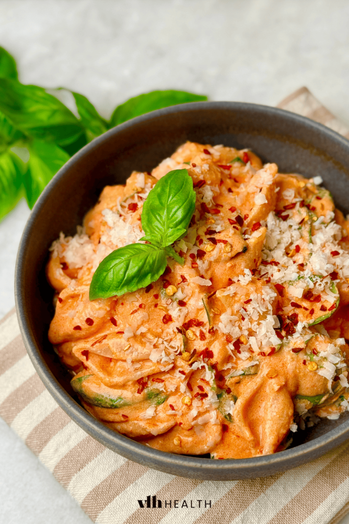 Creamy tomato protein pasta topped with red pepper flakes and parmesan