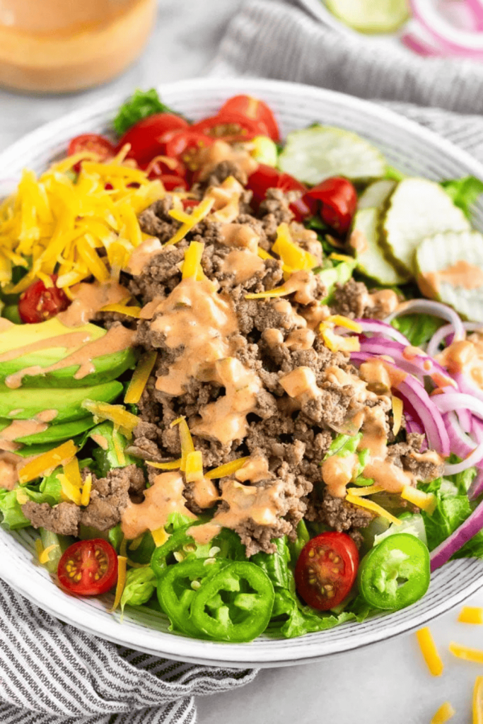 High-protein cheeseburger salad with ground beef, cheddar, pickles, and special sauce