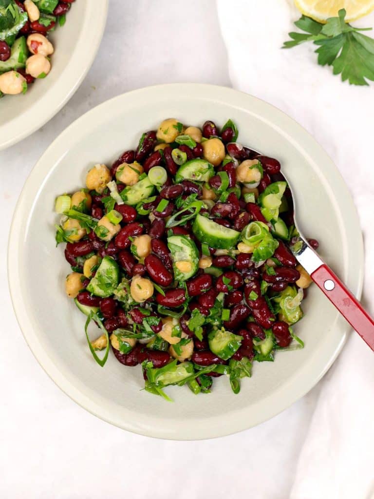 Simple chickpea and kidney bean salad with cucumber and green onion in a ceramic bowl