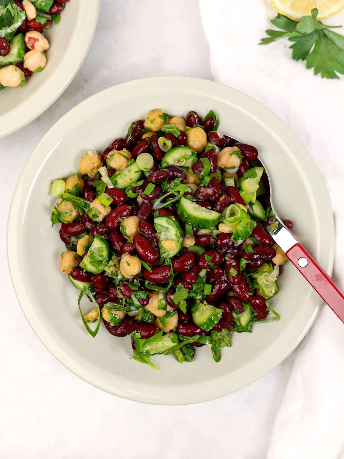 Simple chickpea and kidney bean salad with cucumber and green onion in a ceramic bowl