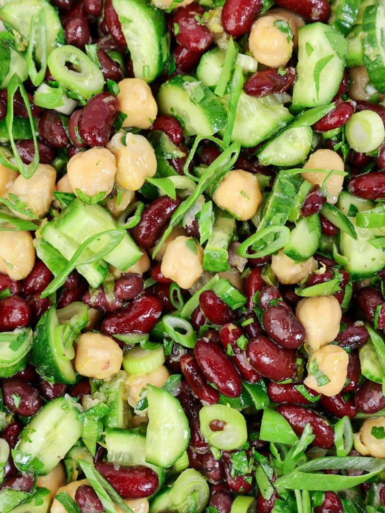 Close-up of simple kidney bean salad coated in lemon-garlic dressing with cucumber and chickpeas