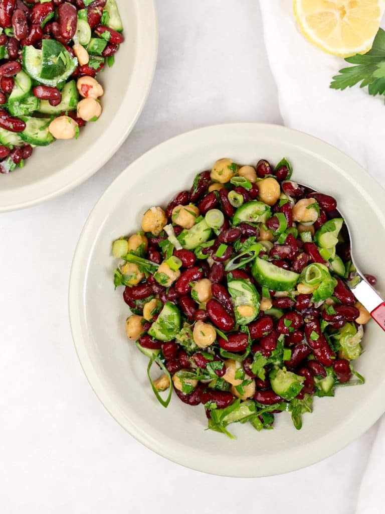 Simple kidney bean salad recipe served in two bowls with lemon and parsley on a linen napkin