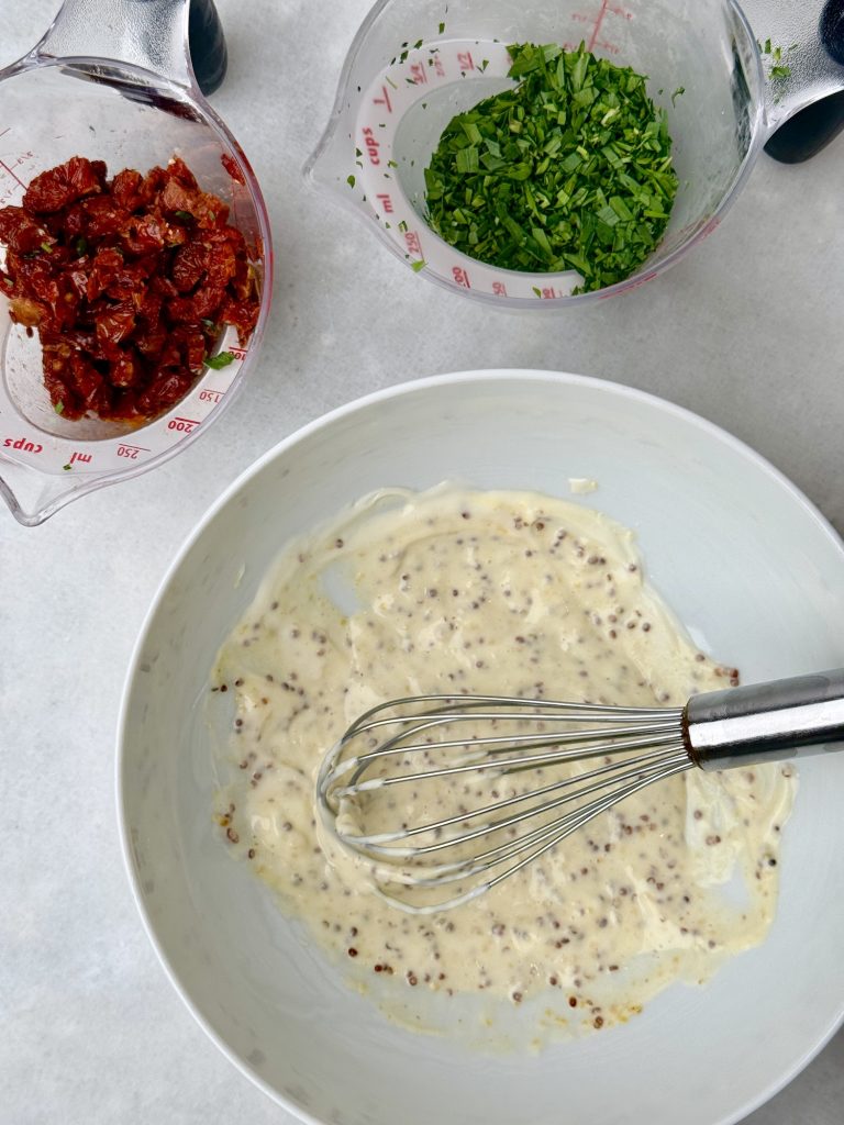 Whisked mustard and mayo dressing for egg salad, with fresh tarragon and chopped sun-dried tomatoes in prep bowls