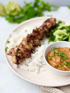 Juicy grilled chicken satay skewer with coconut rice and thick peanut sauce, perfect for summer grilling.