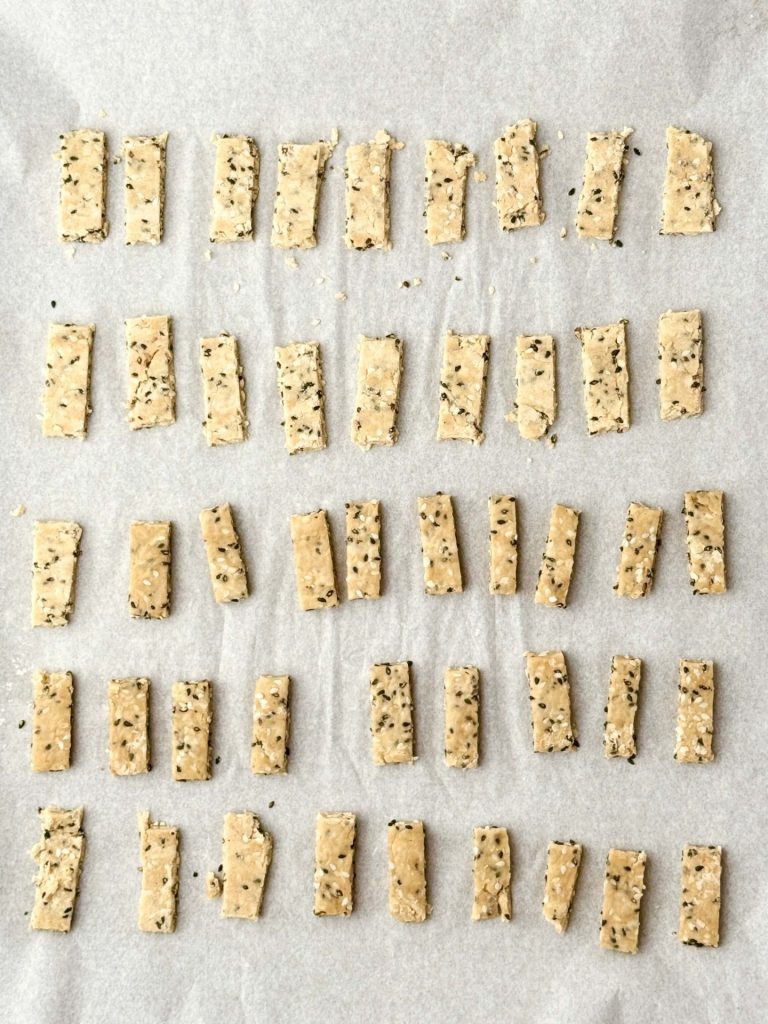 Gluten-free sesame sticks on a parchment-lined tray, ready to bake and become a crunchy topping for the Erewhon Asian Chicken Salad recipe.