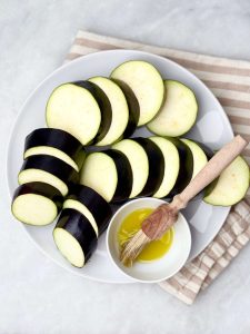 Preparing eggplant for lamb kofta and tzatziki — sliced rounds ready to grill, brushed with olive oil for charred flavor.