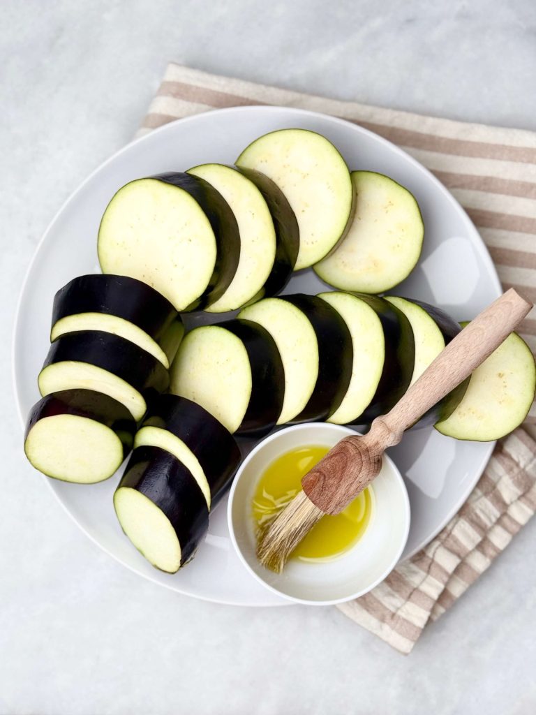 Preparing eggplant for lamb kofta and tzatziki — sliced rounds ready to grill, brushed with olive oil for charred flavor.