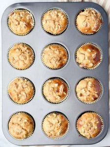 Overhead view of high protein banana bread muffins baked in a muffin pan with golden tops and chopped walnuts.