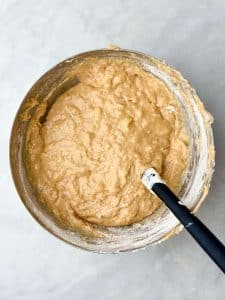 Large mixing bowl with high protein banana bread muffin batter, showing smooth texture and visible banana pieces.