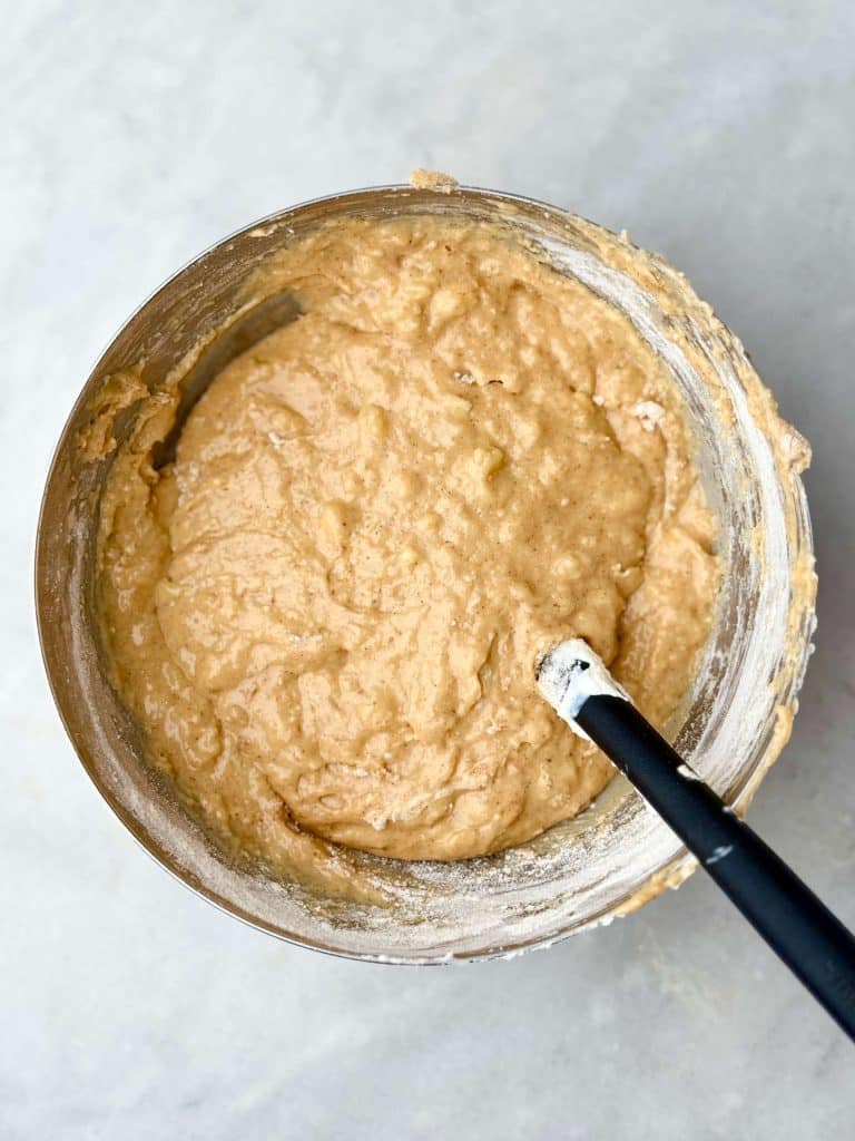 Large mixing bowl with high protein banana bread muffin batter, showing smooth texture and visible banana pieces.