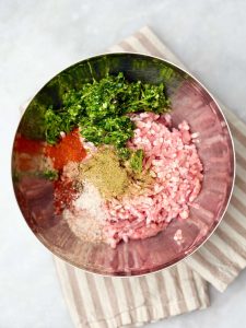 Ingredients for lamb kofta and tzatziki — ground lamb, parsley, cumin, and paprika prepped in a mixing bowl.