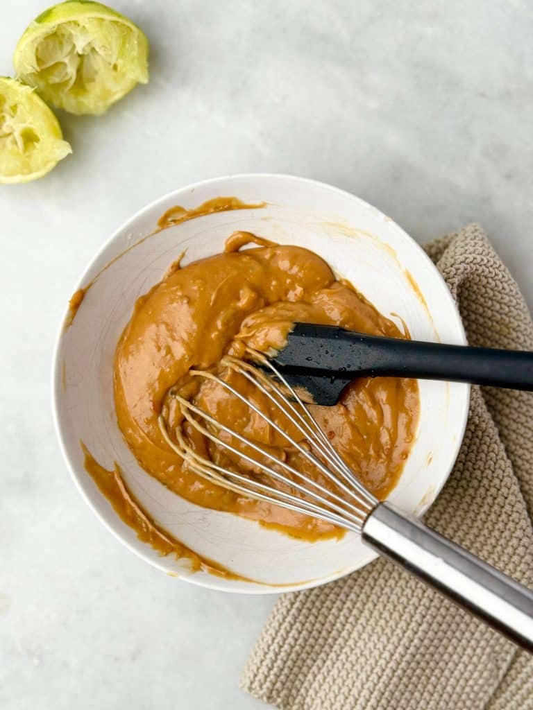 Creamy homemade peanut sauce with lime, garlic, and chili, whisked to perfection for satay dipping.