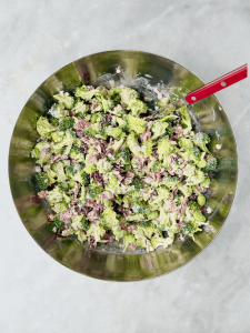 Finished bowl of high protein broccoli salad served on a neutral background, showcasing colorful textures and a protein-rich mix of veggies and toppings.