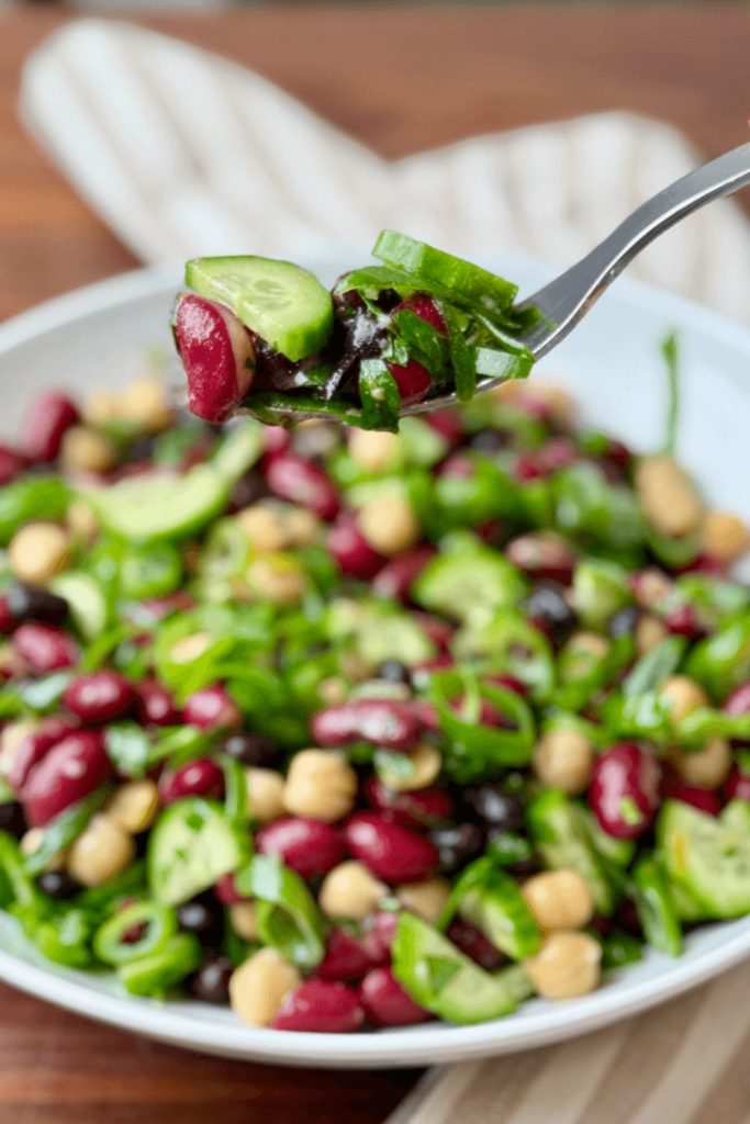 Protein-packed bean salad with chickpeas, kidney beans, black beans, and cucumber — a fiber-rich vegetarian lunch idea.