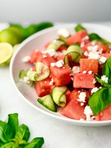Watermelon Feta Salad with Cucumber and fresh basil, seasoned with chili-lime and styled with squeezed limes and herbs.