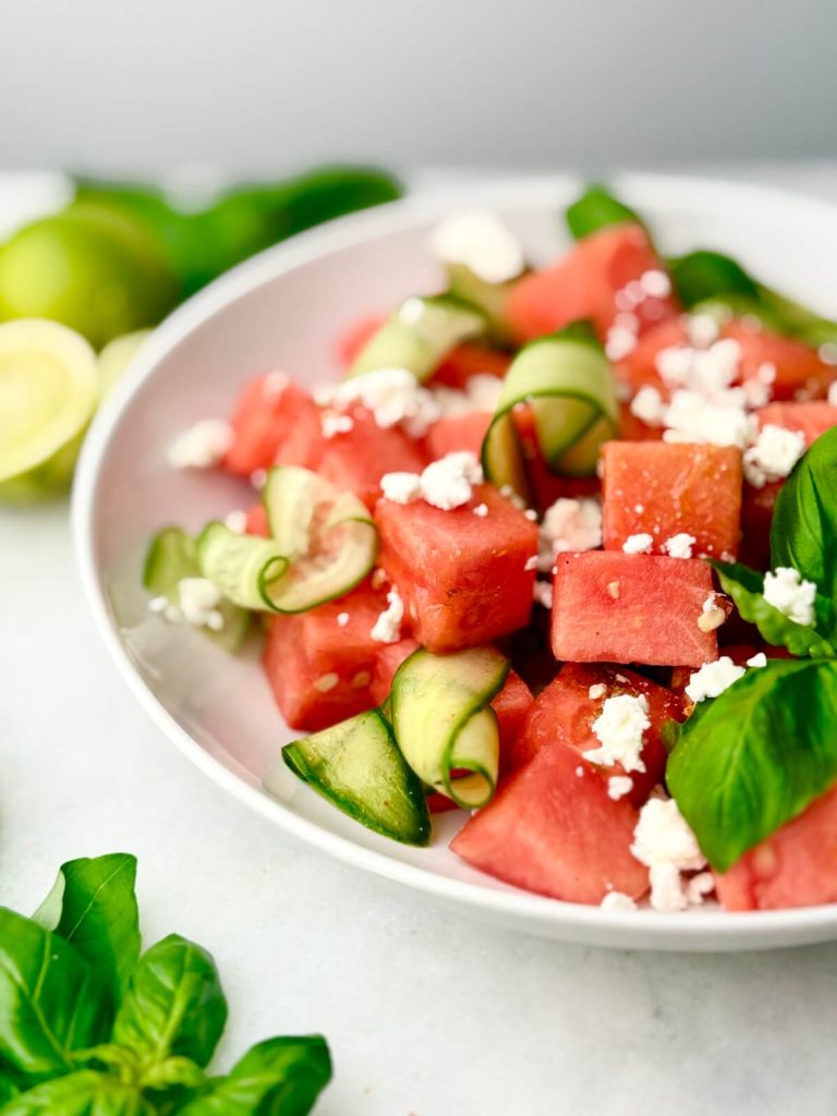 Watermelon Feta Salad with Cucumber and fresh basil, seasoned with chili-lime and styled with squeezed limes and herbs.