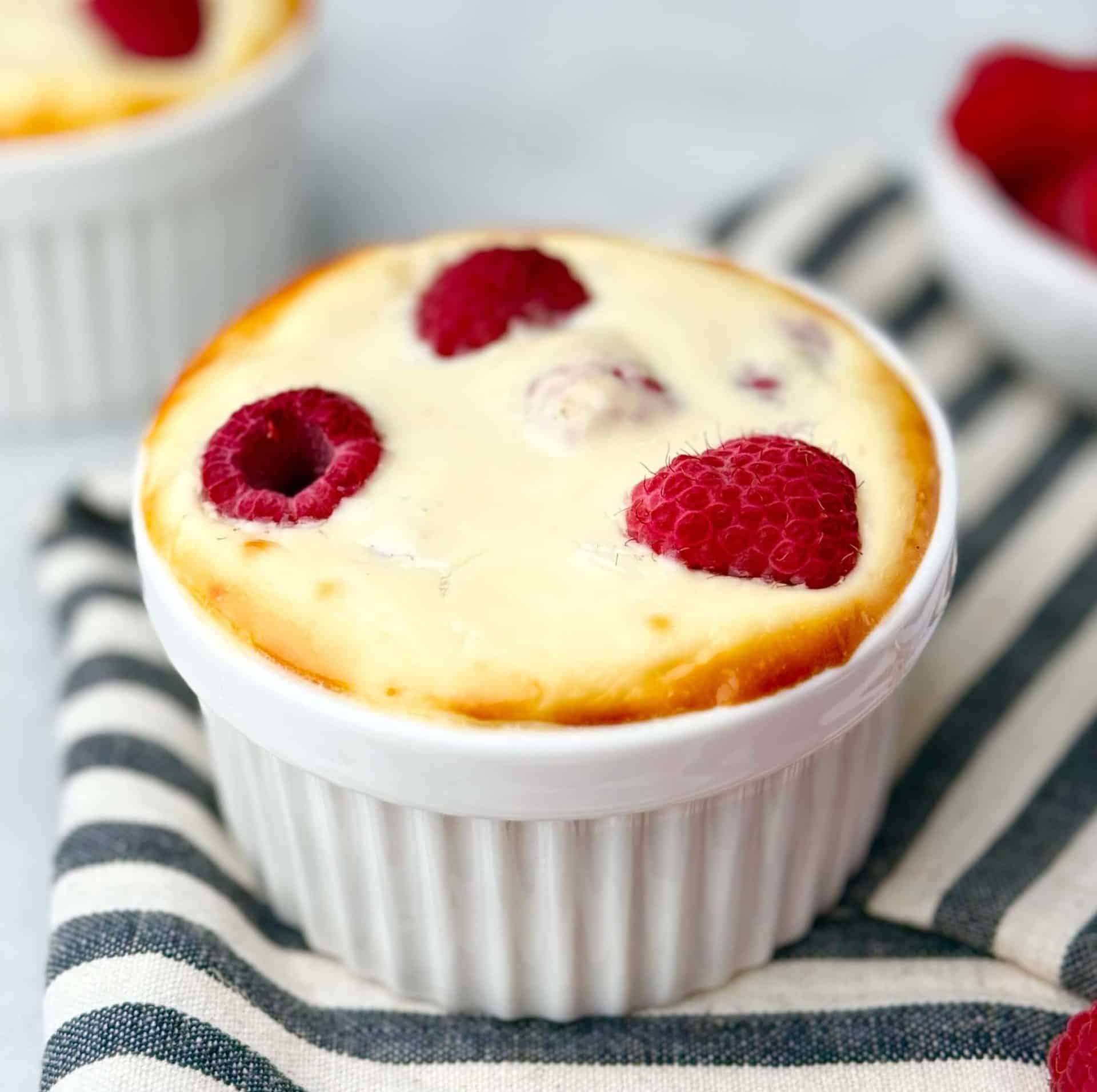 Angle view of single-serve raspberry yogurt bake, lightly golden edges and fresh berries on top.