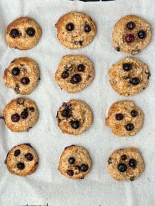 Overhead shot of twelve high protein breakfast cookies on baking sheet. Sugar-free blueberry cookies made with coconut, hemp hearts, and collagen.