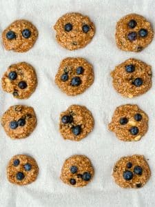 Unbaked high protein breakfast cookie dough with blueberries on parchment. Healthy dairy-free recipe ready to bake.