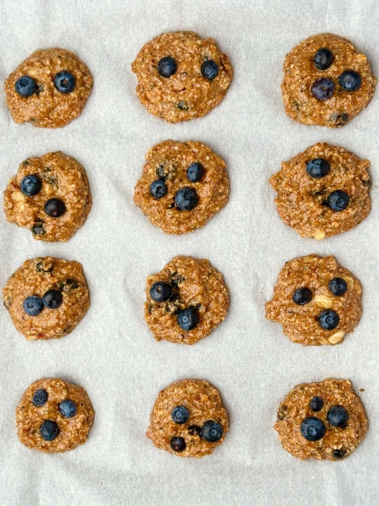 Unbaked high protein breakfast cookie dough with blueberries on parchment. Healthy dairy-free recipe ready to bake.