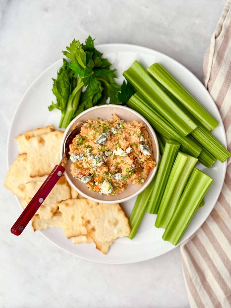 Close-up of creamy buffalo chicken salad topped with blue cheese crumbles and fresh chives.