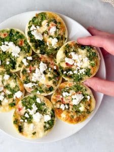 Close-up of finished Starbucks egg white bites recipe in oven, topped with feta and spinach on white plate for meal prep breakfast.