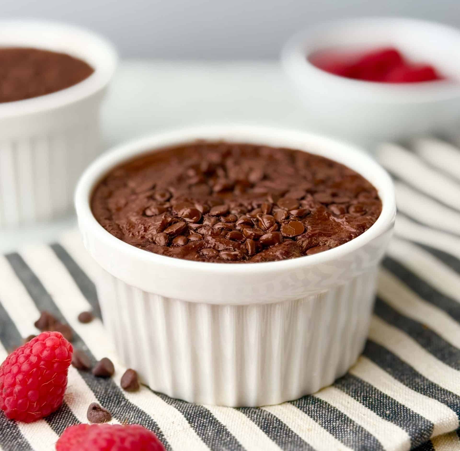 Close-up of a single-serve chocolate protein baked oats recipe with Greek yogurt, baked until golden and topped with chocolate chips, on a striped kitchen towel.