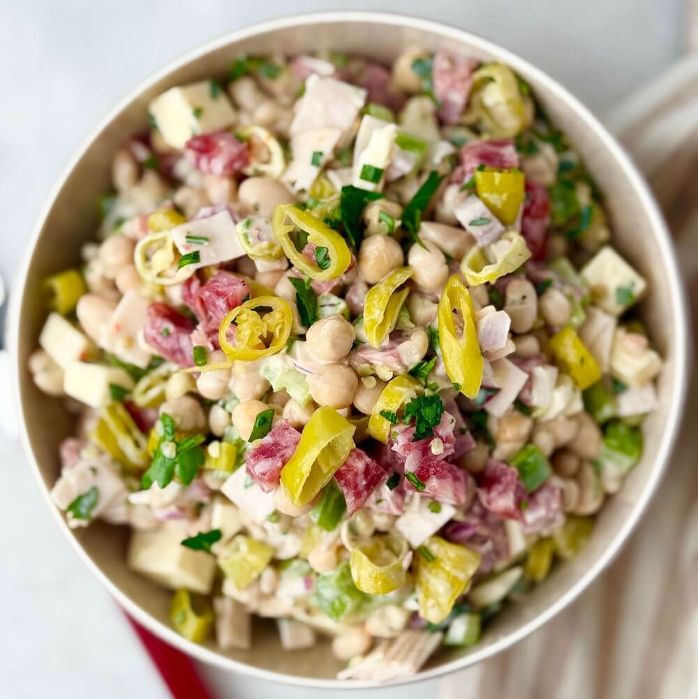 Top down view of Italian grinder bean salad with beans, deli meats, cheese, and vegetables mixed together in a creamy dressing.