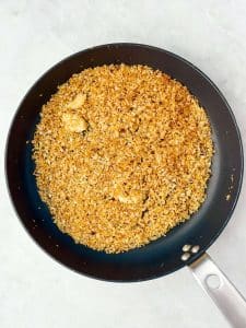 Toasted garlicky panko breadcrumbs in a black skillet for topping green pea pasta. Crunchy spicy breadcrumbs add texture to creamy pea pasta.