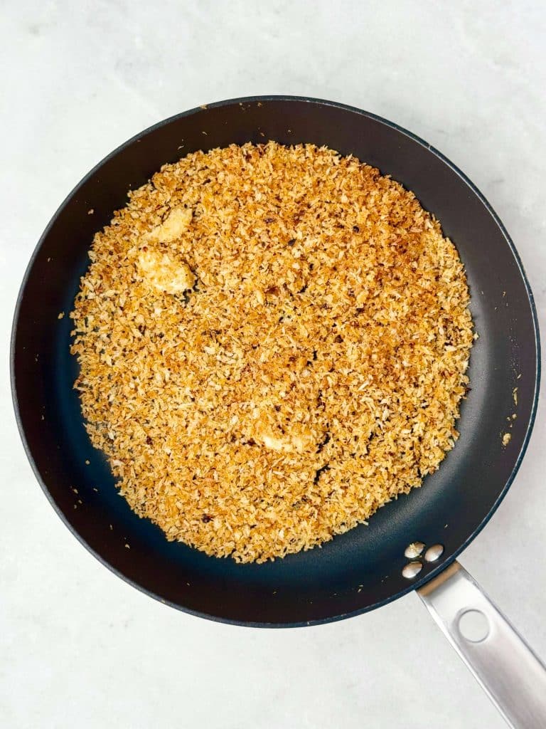 Toasted garlicky panko breadcrumbs in a black skillet for topping green pea pasta. Crunchy spicy breadcrumbs add texture to creamy pea pasta.