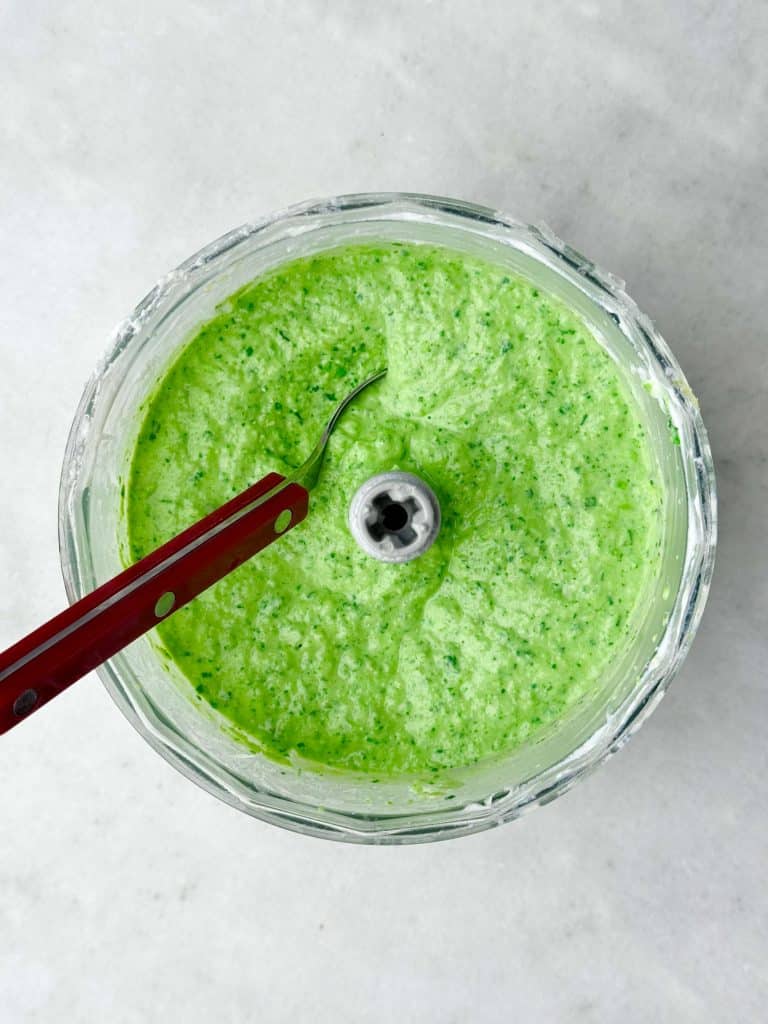 Bright green creamy pea pasta sauce blended with ricotta, basil, and lemon in a food processor.