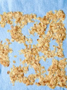 Golden toasted sliced almonds spread on a baking sheet lined with parchment paper for topping spinach strawberry salad.