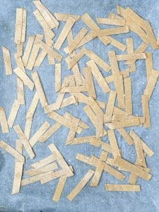 Unbaked tortilla strips arranged on a baking sheet, lightly oiled and ready to crisp in the oven.