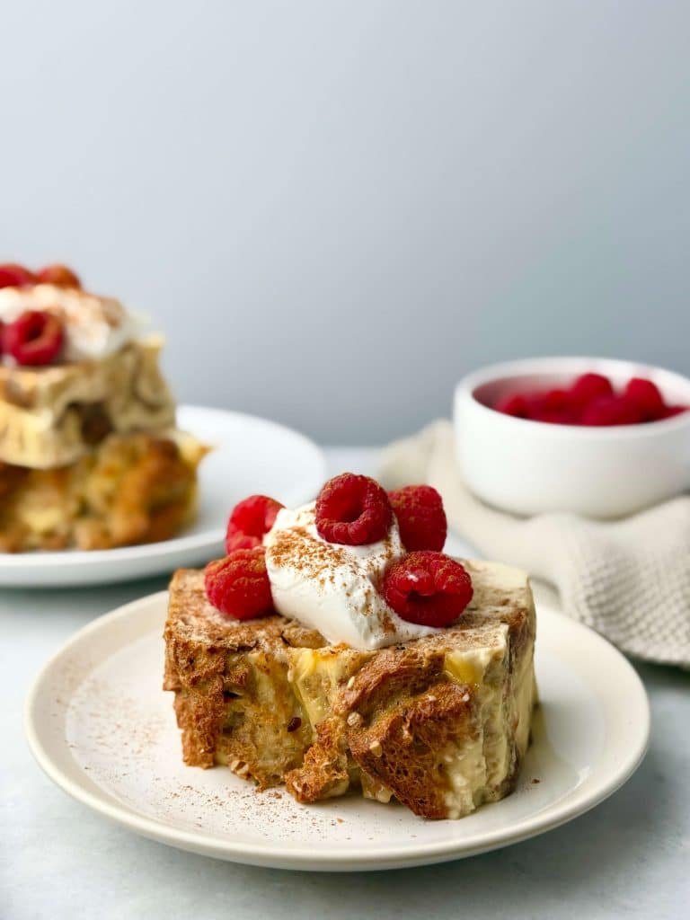 Close-up of high protein French toast bread pudding topped with yogurt, raspberries, and a dusting of cinnamon.