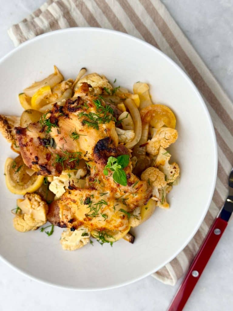 Overhead angle of plated chicken and potatoes with roasted cauliflower and fresh dill garnish.