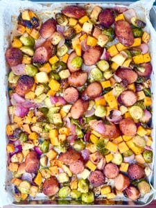 Fully cooked fall sausage and veggie sheet pan with golden brown sausage, sweet potatoes, and Brussels sprouts.