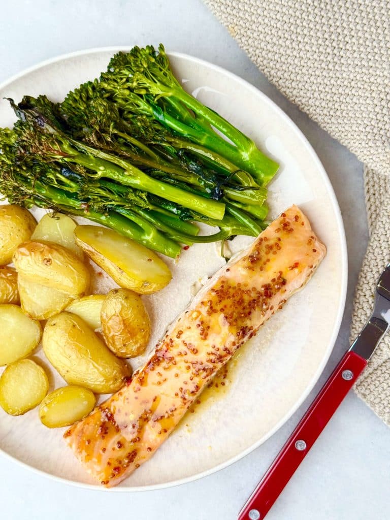 Overhead view of a complete plated meal with roasted baby potatoes, broccolini, and honey mustard salmon.