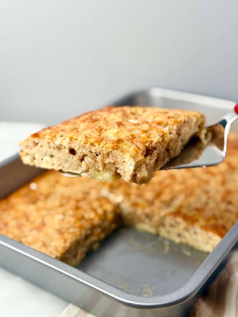 Fluffy sheet pan banana protein pancake slice lifted from baking dish, golden and soft inside.