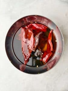 Dried guajillo and ancho chiles soaking in hot water to soften for birria soup sauce.