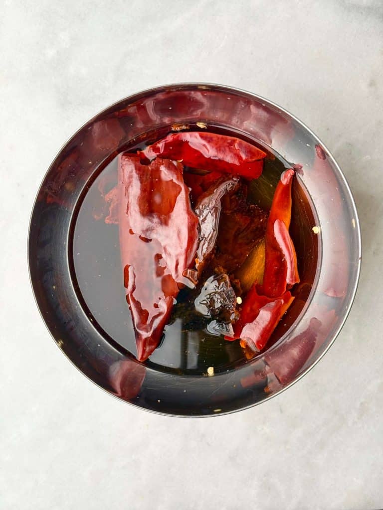 Dried guajillo and ancho chiles soaking in hot water to soften for birria soup sauce.