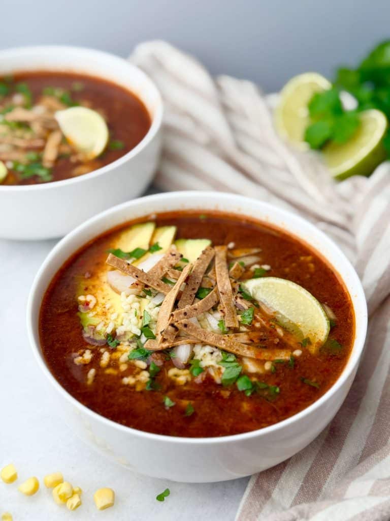 Hearty birria taco soup served in bowls, garnished with tortilla strips, lime wedges, and cilantro.