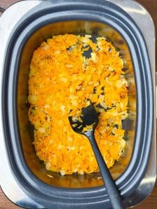 Sautéed onion, garlic, and grated carrots in a crockpot for broccoli cheddar soup